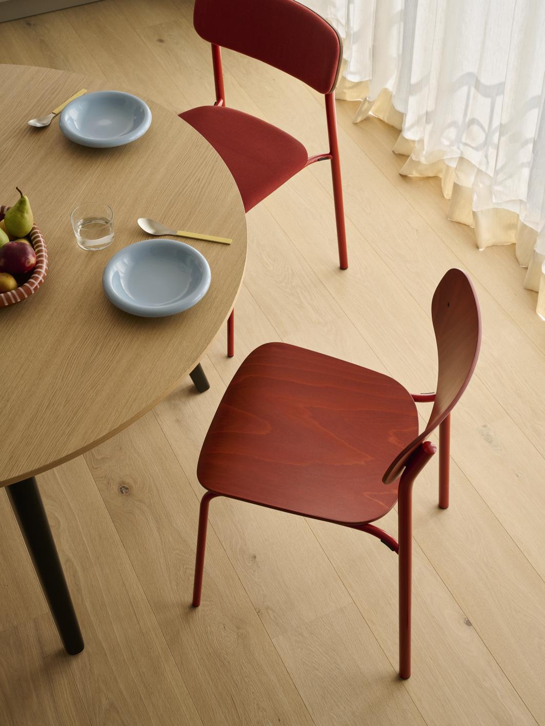 Zwei rote S 243 Stahlrohr Stühle von Thonet an einem Esstisch mit Geschirr.