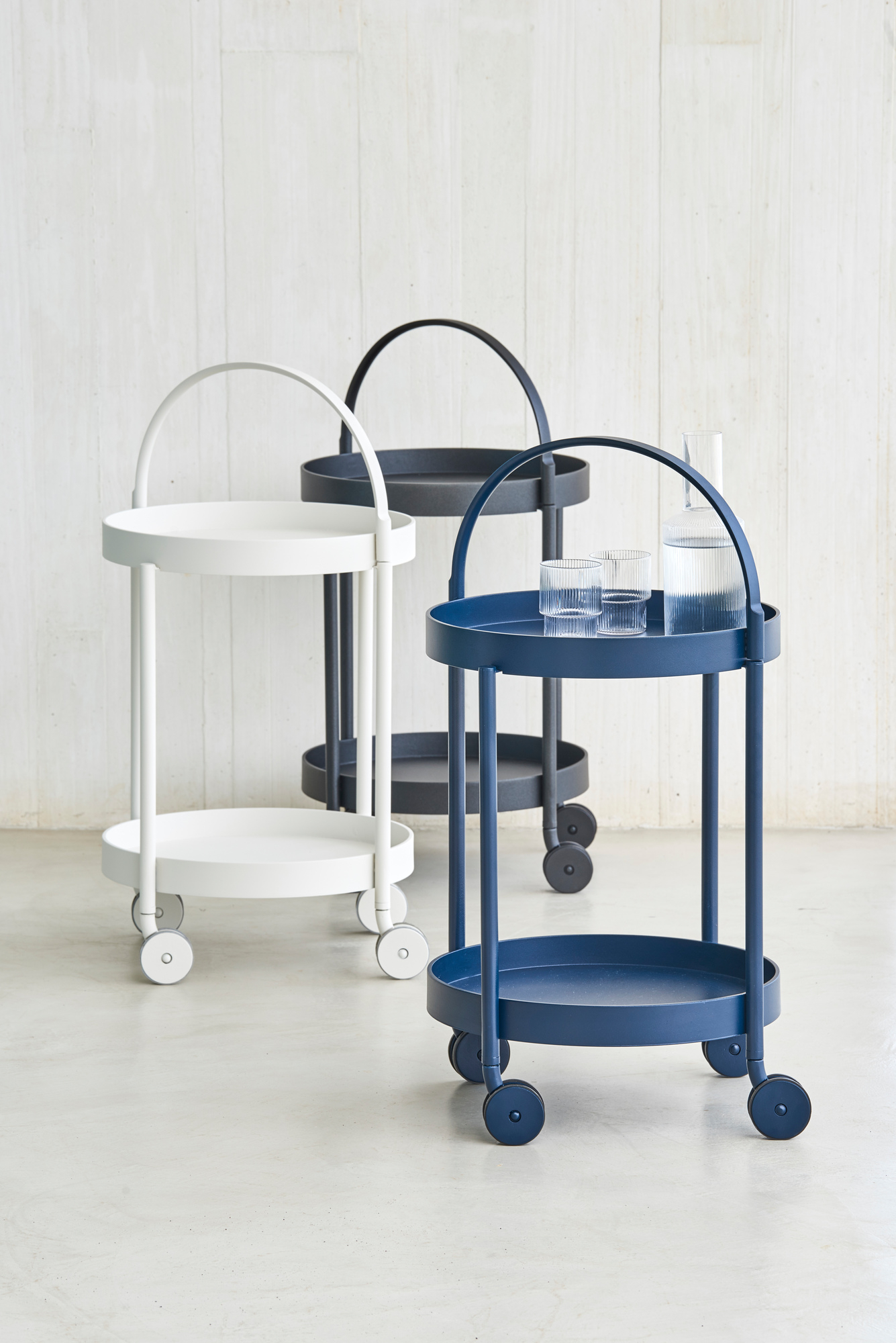 Cane-Line Roll Barwagen in Weiß, Grau und Blau mit Gläsern und Wasserflasche.