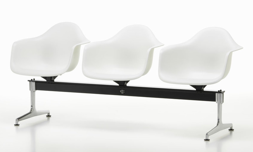 Eames Plastic Armchair RE auf Traverse von Vitra, Wartebank mit drei weißen Kunststoffschalen und schwarzem Gestell.