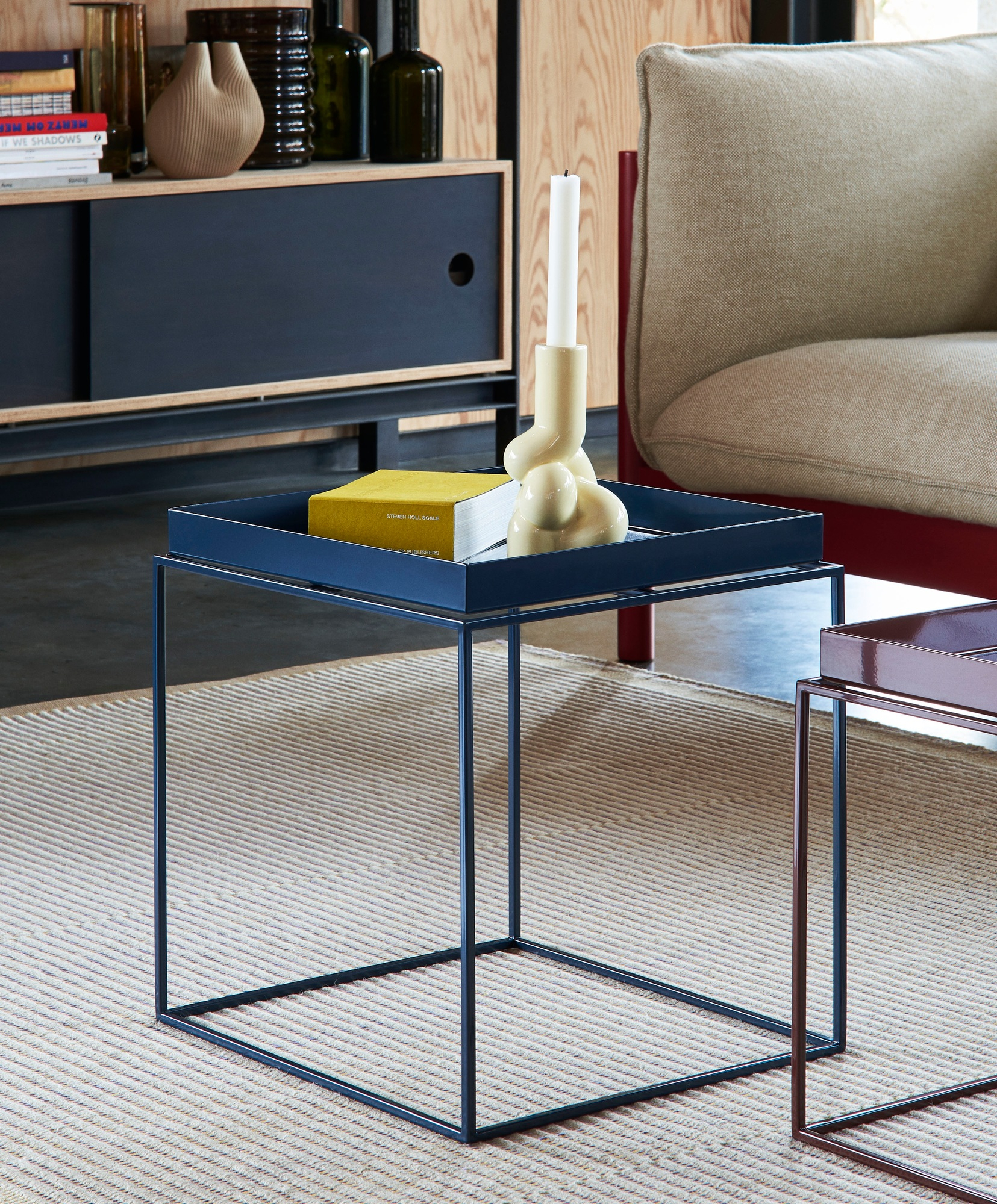 Detailaufnahme des Tapis Teppich Hay, kombiniert mit einem blauen Couchtisch, Buch und Kerzenständer.