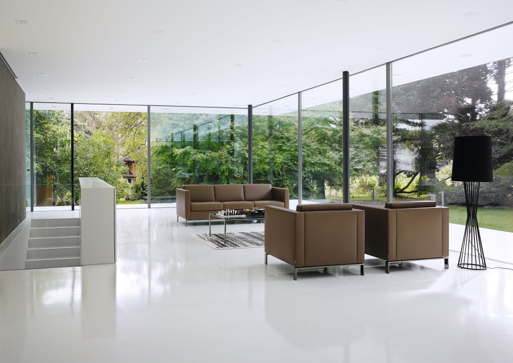 Helles Wohnzimmer mit braunem FOSTER Sofa von Walter Knoll und passenden Sesseln.