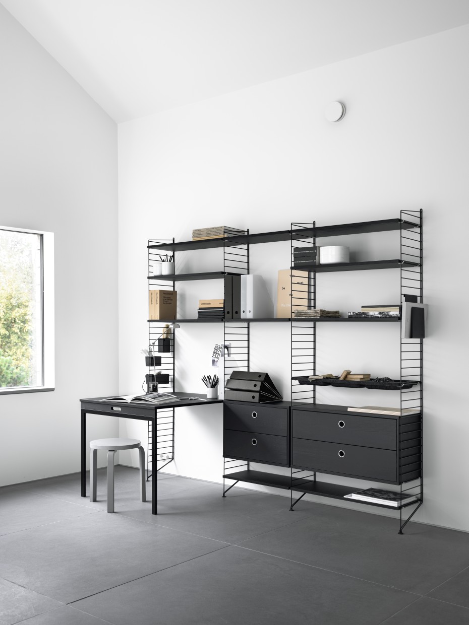 Schwarzes String Furniture Regalsystem mit Schreibtisch und Schubladen in modernem Wohnzimmer.