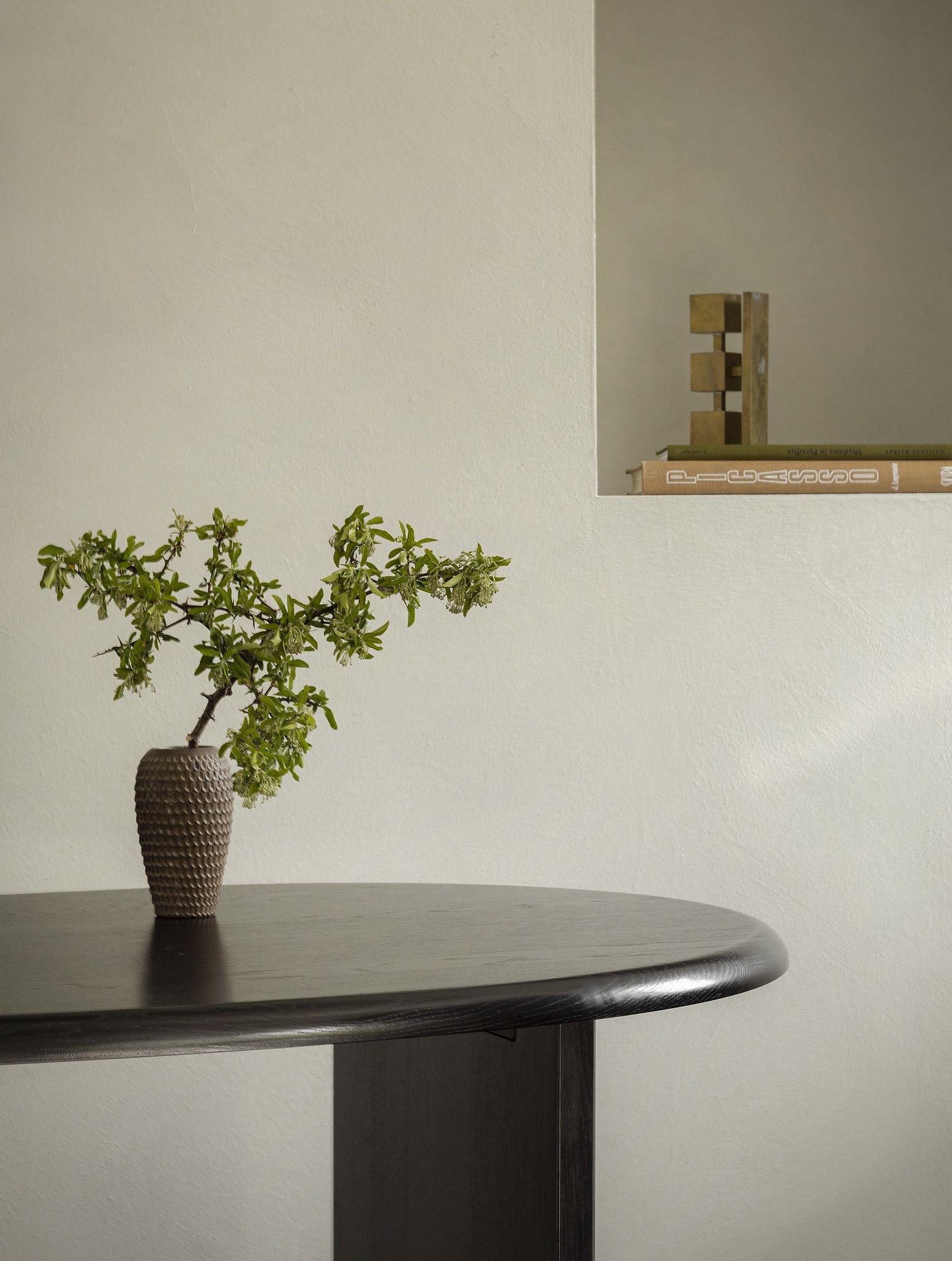 Nahaufnahme des Audo Copenhagen Eclipse Desk Schreibtischs mit Vase und grünen Zweigen.
