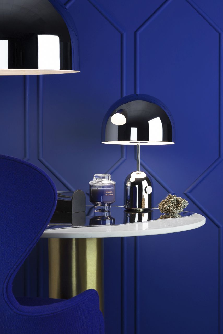 Nahaufnahme der Bell Tischleuchte LED von Tom Dixon auf einem Beistelltisch mit blauer Wand.