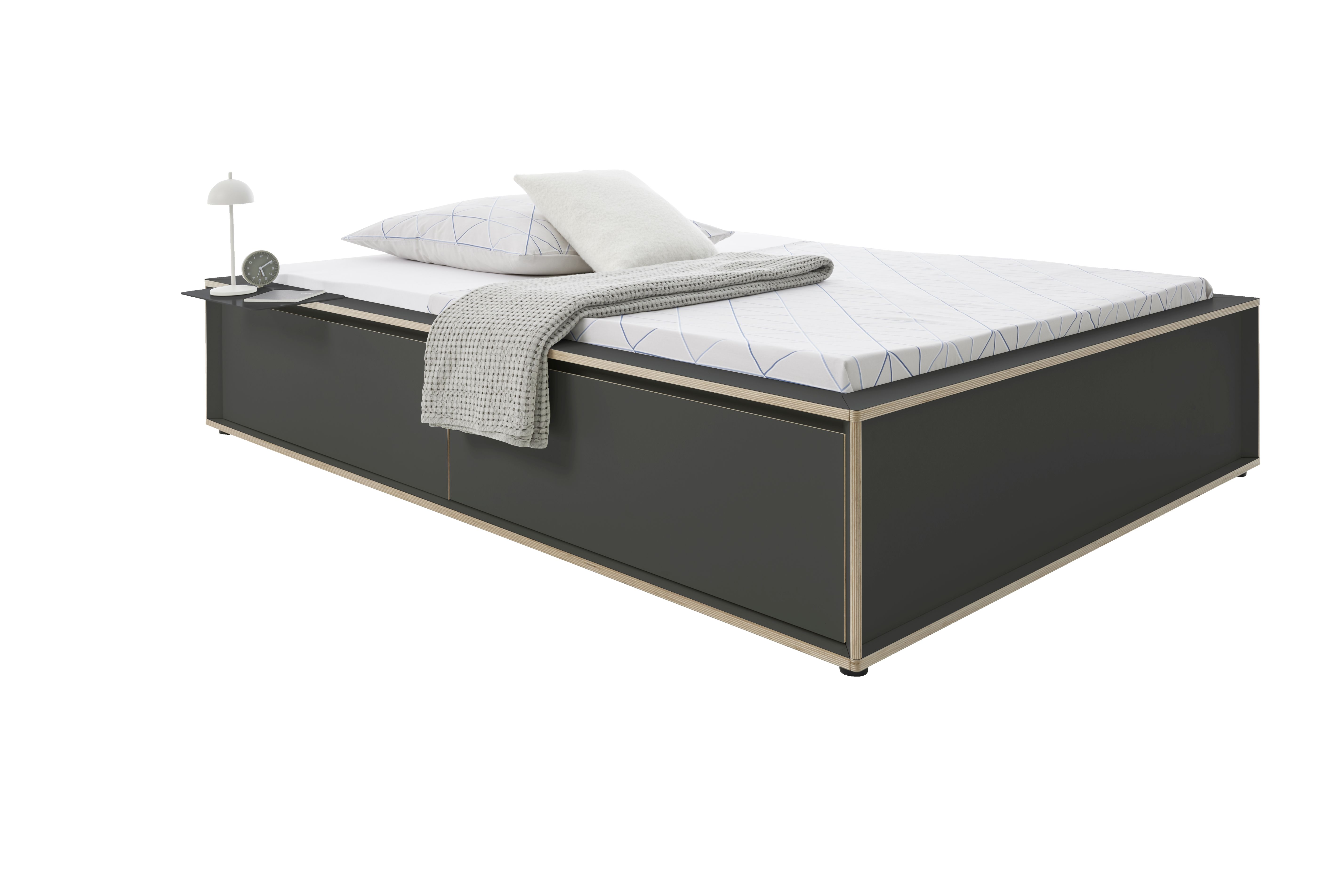Spaze Bett von Müller Möbelwerkstätten in Anthrazit mit Nachttisch, Kissen und Decke.