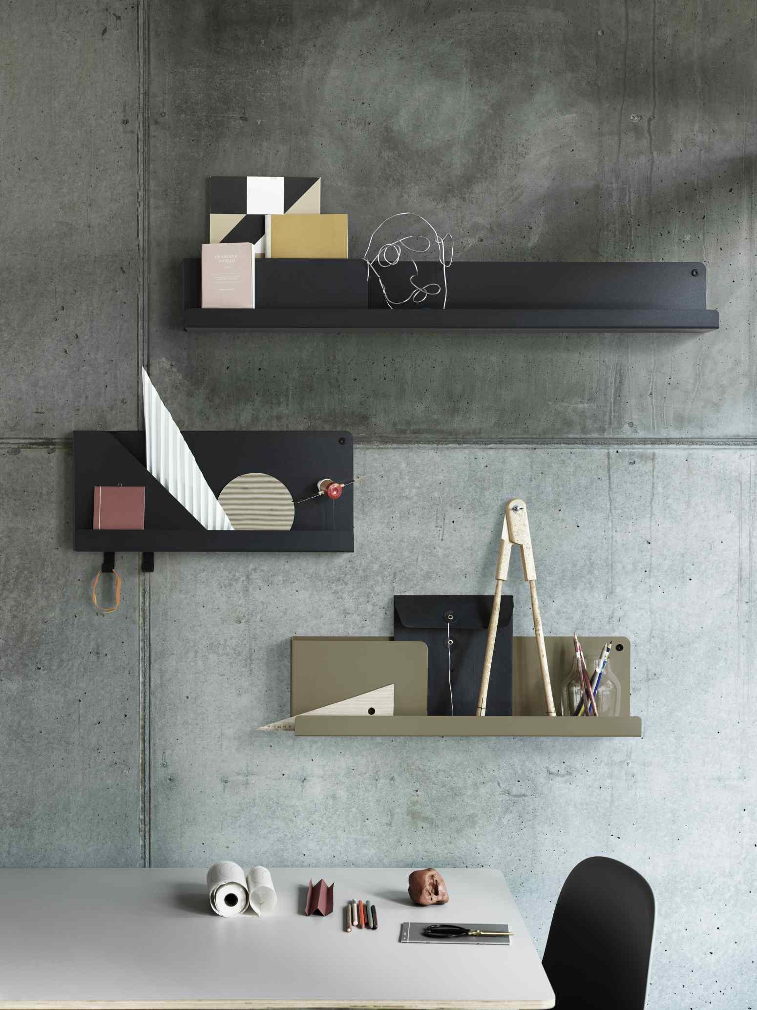 Muuto Folded Shelves Wandregal in Schwarz und Olivgrün an einer Betonwand mit Dekoration.
