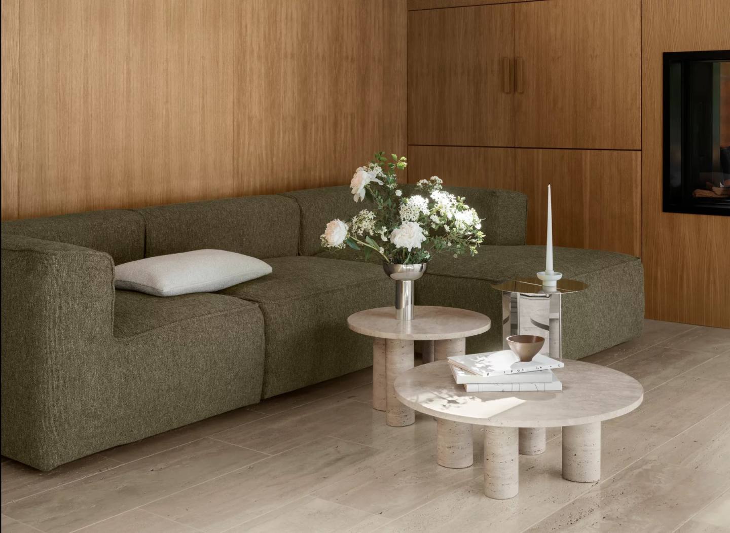Nahaufnahme von zwei runden Couchtischen aus Travertin, darunter der Volos Couchtisch von Blomus, in einem Wohnzimmer.