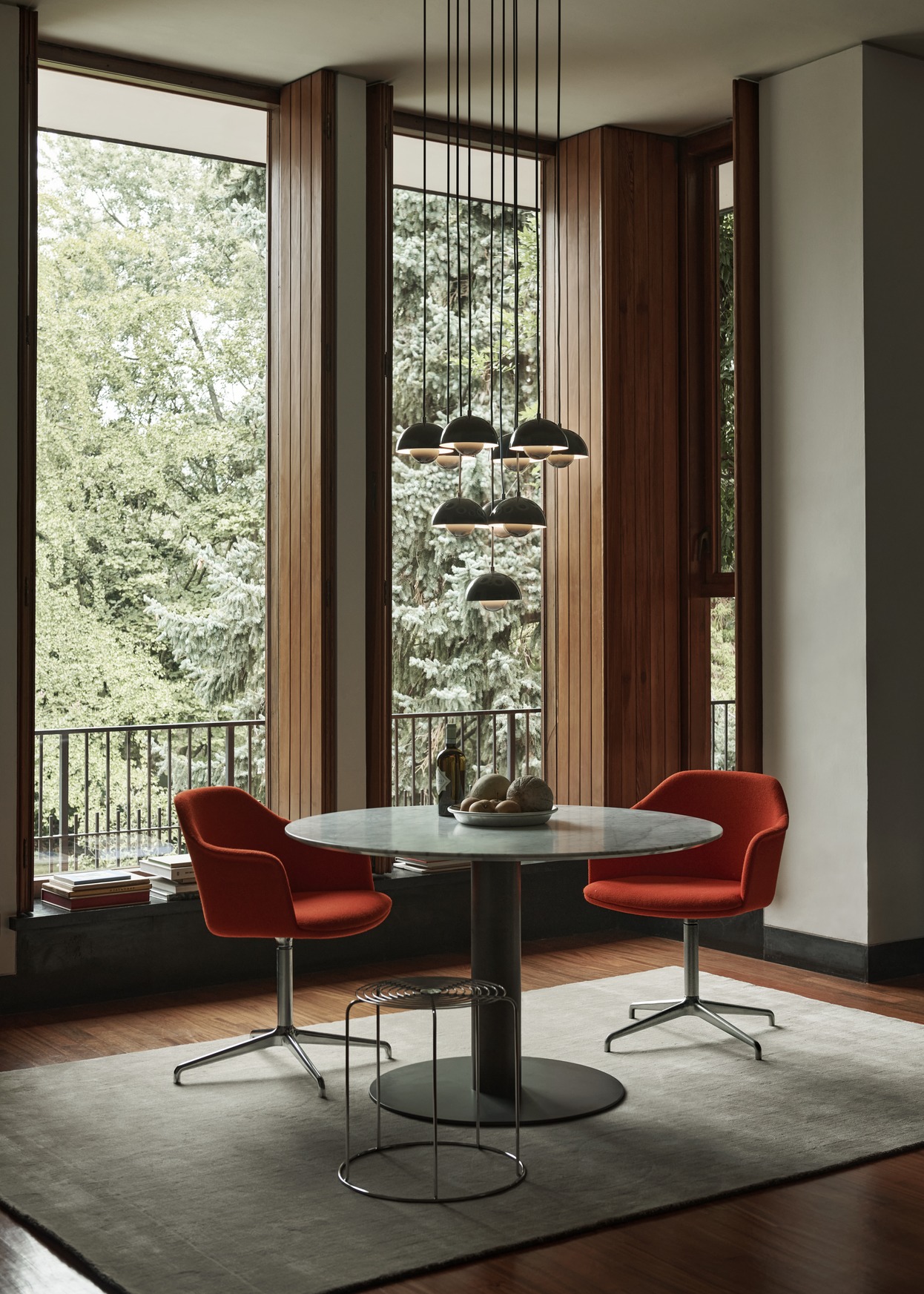 AndTradition Wire Stool VP11 als Beistelltisch im Esszimmer mit Marmortisch und roten Stühlen.