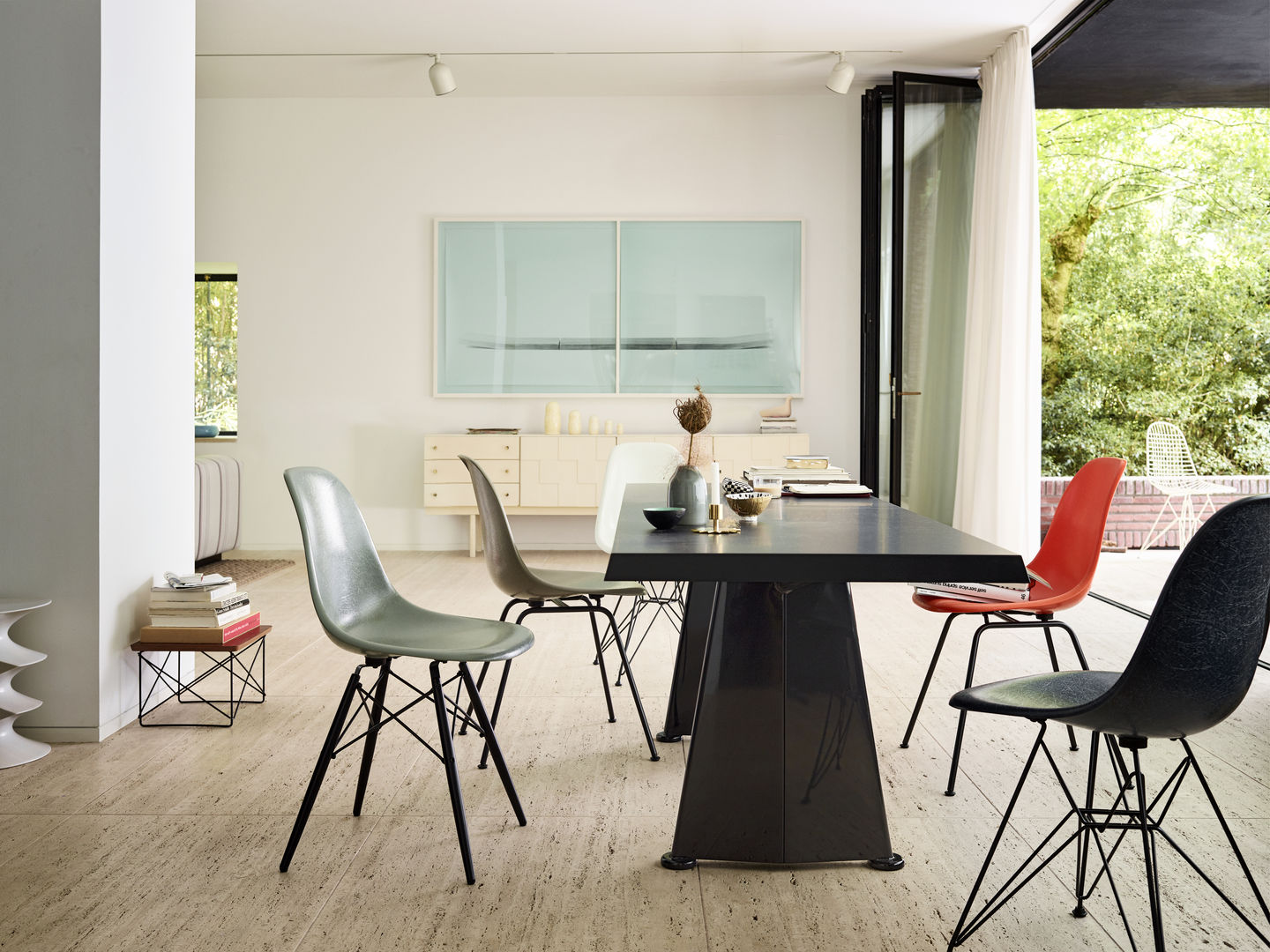 Esszimmer mit Esstisch und mehreren bunten Eames Fiberglass Stühlen DSW von Vitra mit Sitzpolster.