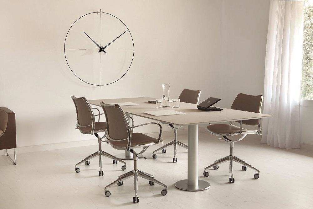Minimalistische Bilbao Wanduhr von Nomon in Weiß über einem modernen Konferenztisch im Büro.
