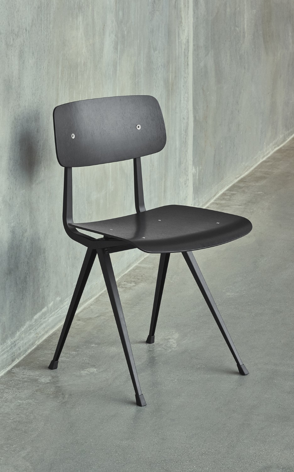 Schwarzer Result Chair Stuhl von Hay mit Holz-Sitzfläche und filigranem Stahlgestell vor einer grauen Wand.