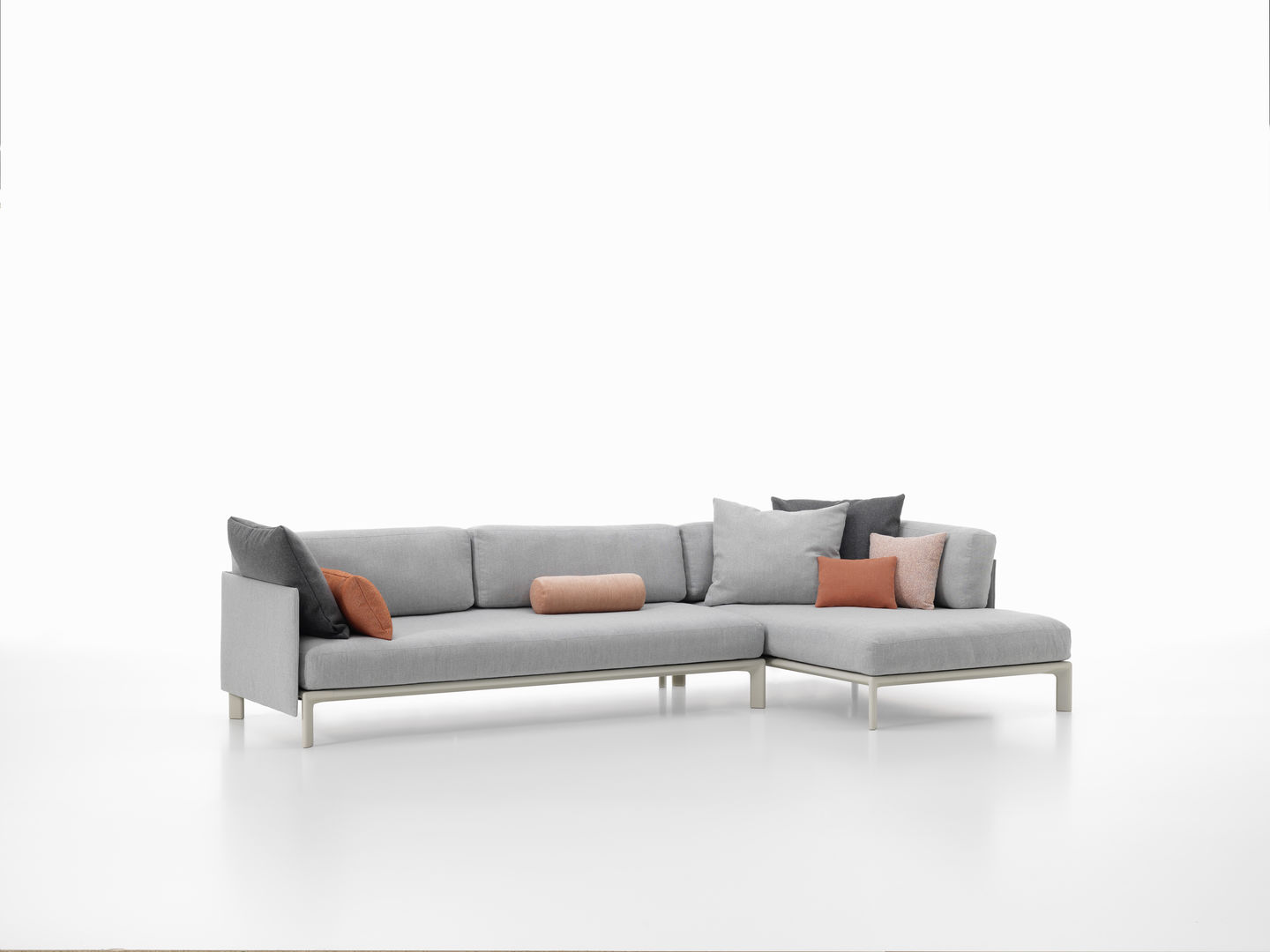 Graues Anagram Sofa von Vitra mit Plattform, verschiedenen Kissen und Metallgestell auf weißem Hintergrund.