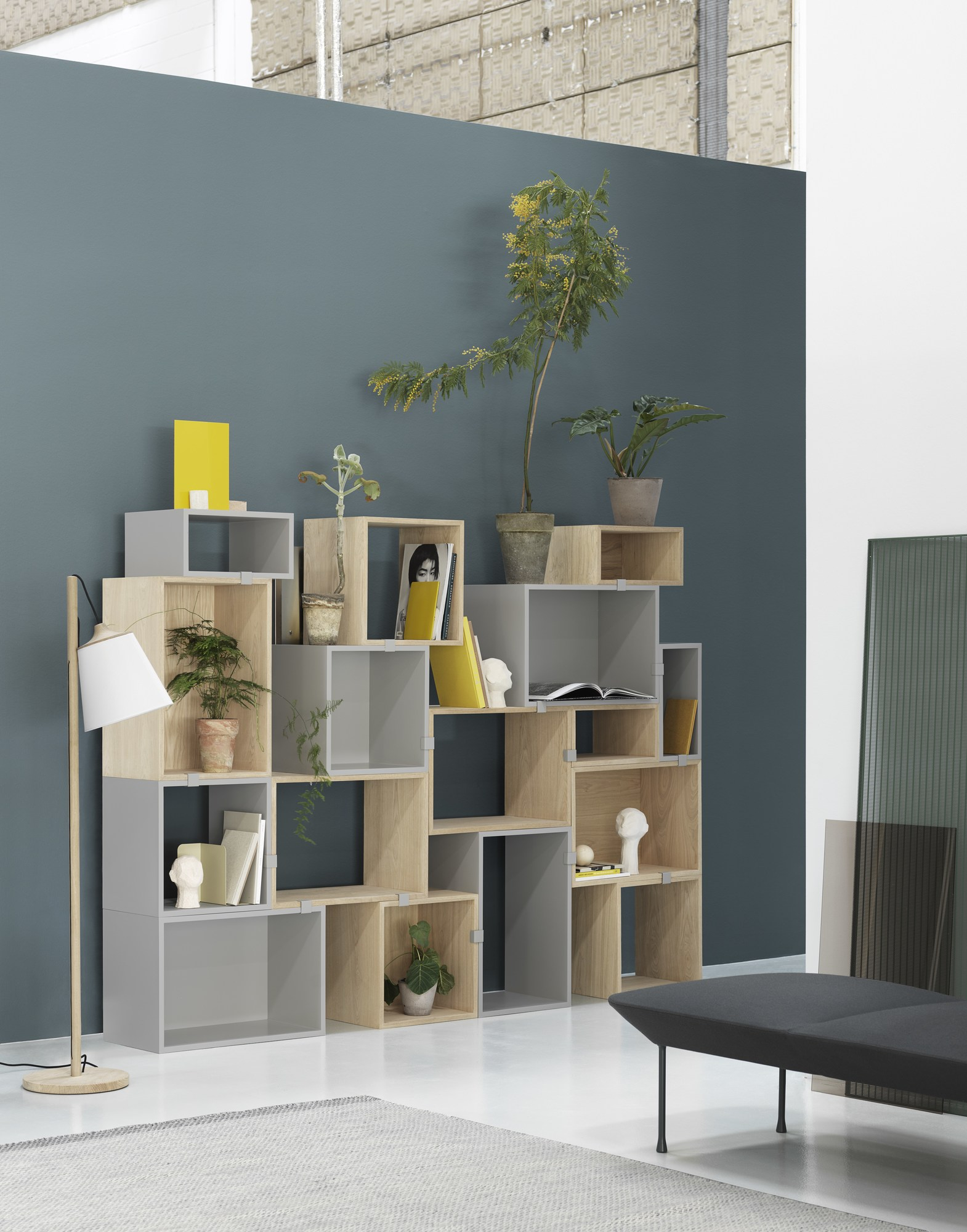 Muuto Stacked Storage System 2.0 Regalsystem aus Holz und Grau, dekoriert mit Pflanzen und Büchern.