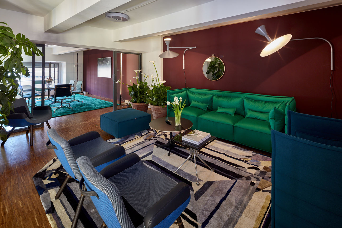 Wohnzimmer mit zwei blauen East River Chair Sesseln von Vitra und grüner Couch.