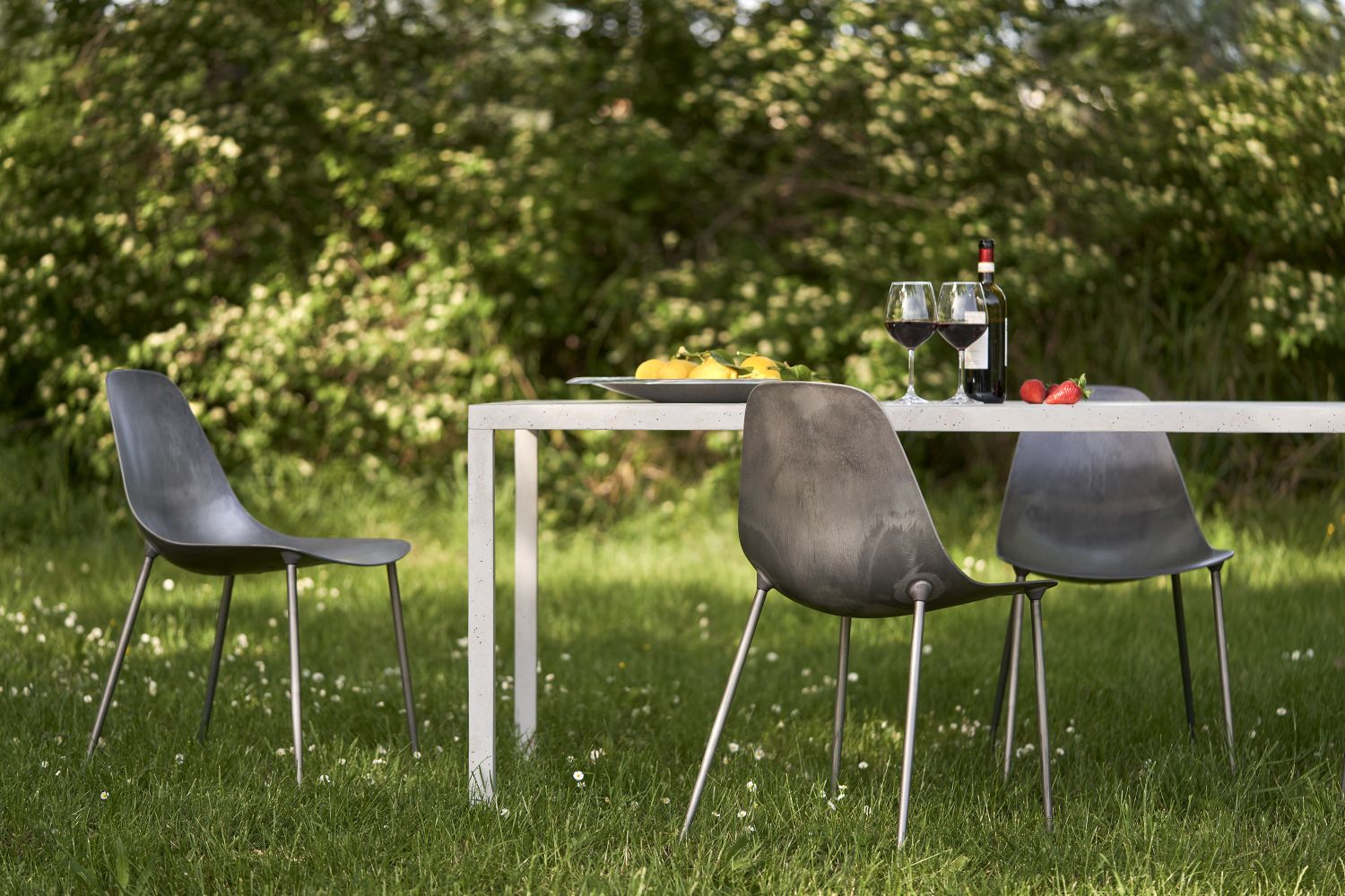 Mammamia Raw Stühle von Opinion Ciatti auf einer Terrasse mit Tisch, Wein und Snacks.