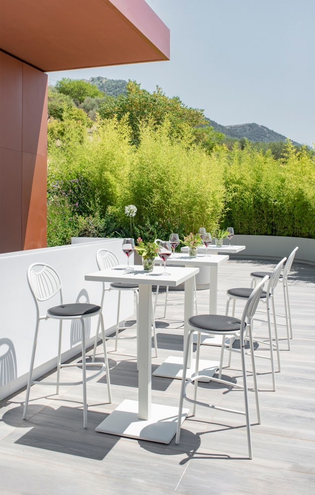 Weiße Coupole Barhocker von Emu Outdoor an Bartischen auf einer Terrasse mit grüner Aussicht.