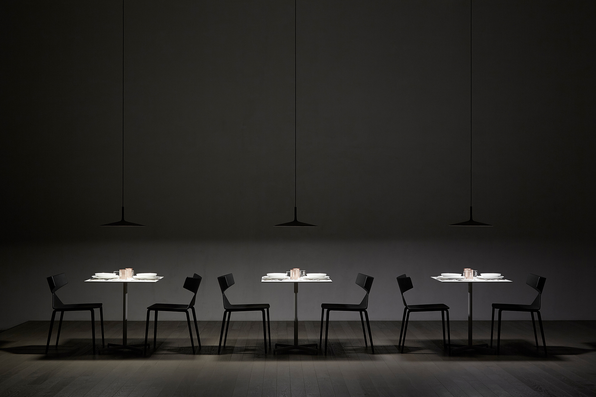 Aplomb LED Pendelleuchten von Foscarini über Esstischen mit Gedeck in dunklem Ambiente.