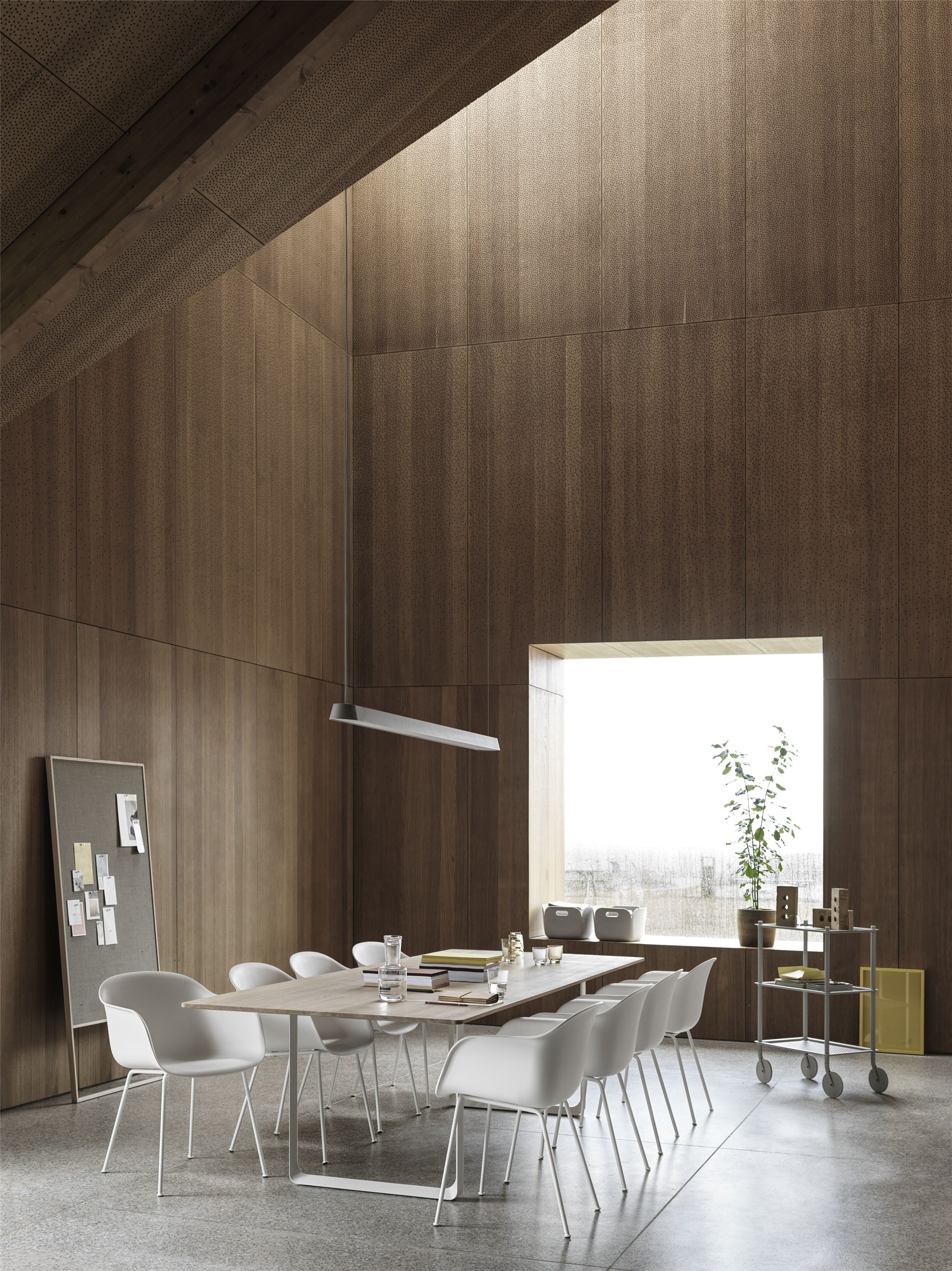 Heller Konferenzraum mit Fiber Armchair Tube Base Stühlen von Muuto um einen Holztisch.
