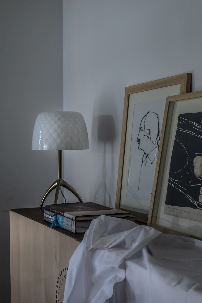 Nahaufnahme der Lumiere Tischleuchte von Foscarini mit weißem Schirm und goldenem Stativfuß.