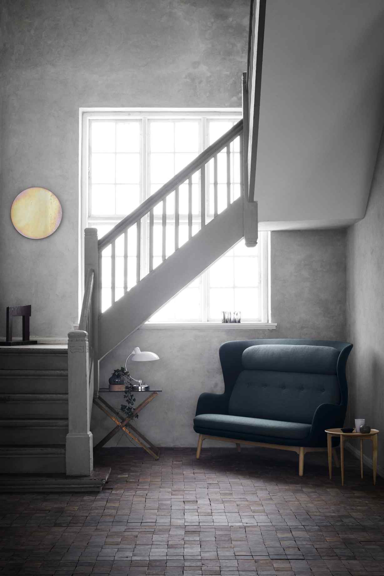 Elegantes, dunkelblaues Ro 2-Sitzer Sofa von Fritz Hansen im skandinavischen Design neben einer Treppe.