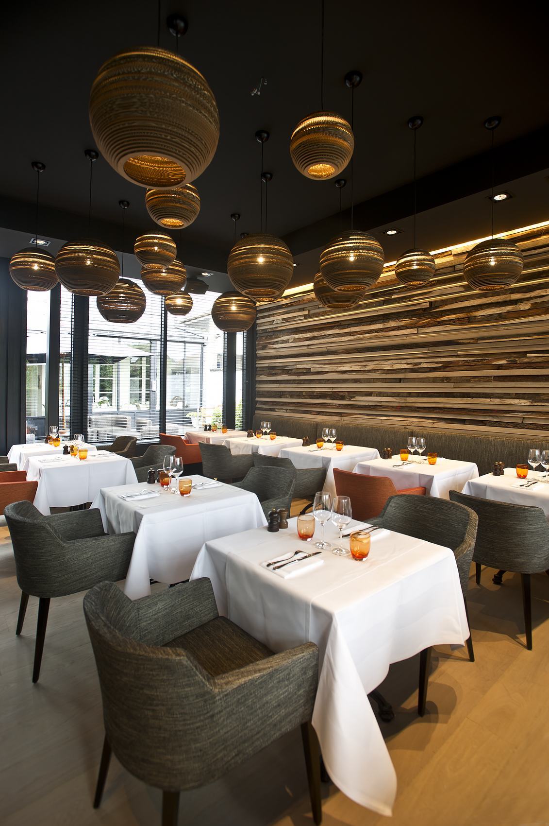 Innenaufnahme eines Restaurants mit Graypants Moon18 Scraplights Hängeleuchten aus recycelter Pappe über gedeckten Tischen.
