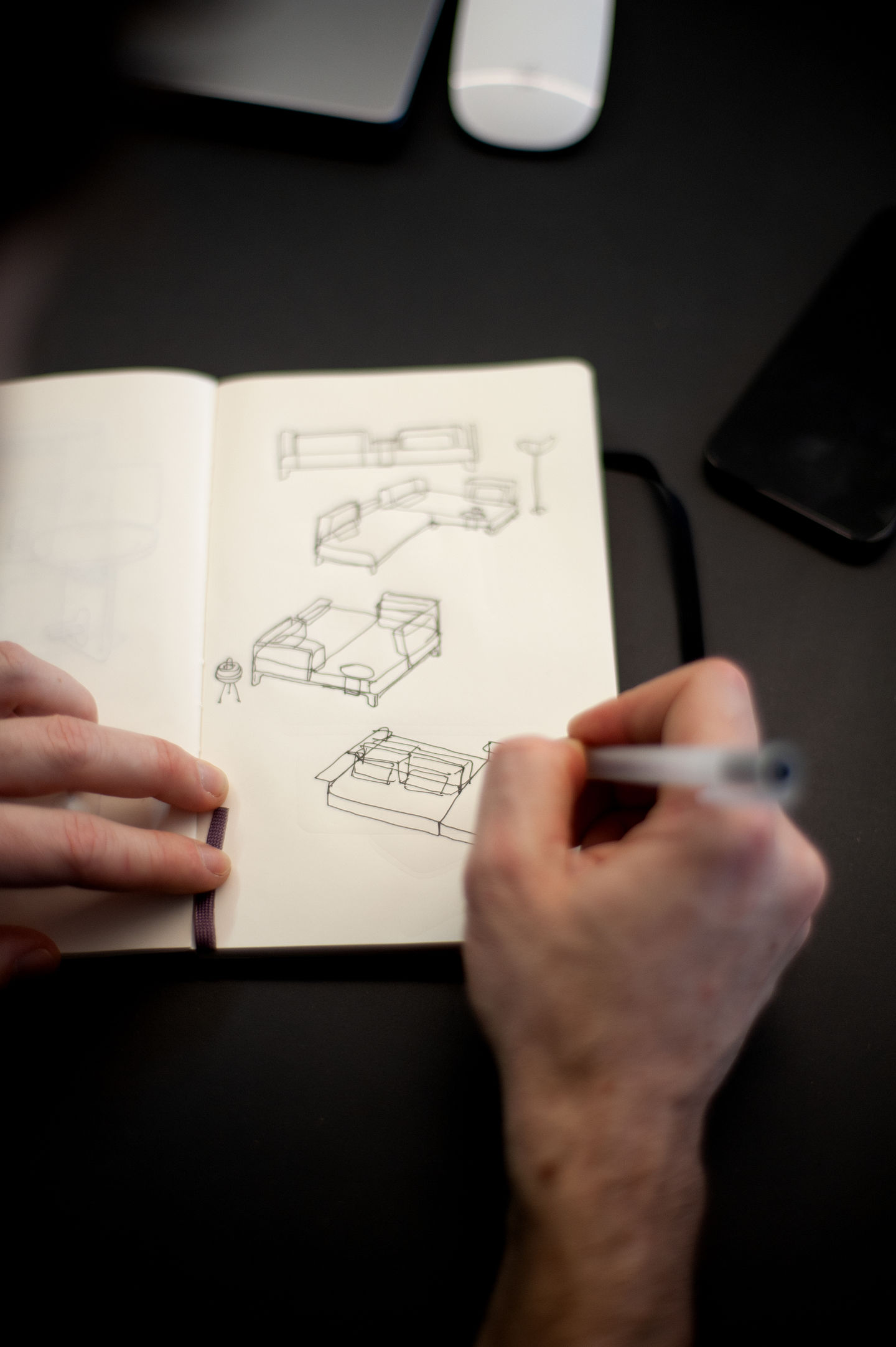 Skizzen von Möbeldesign: Hand zeichnet Sofa, Bett und Lampe in Notizbuch.