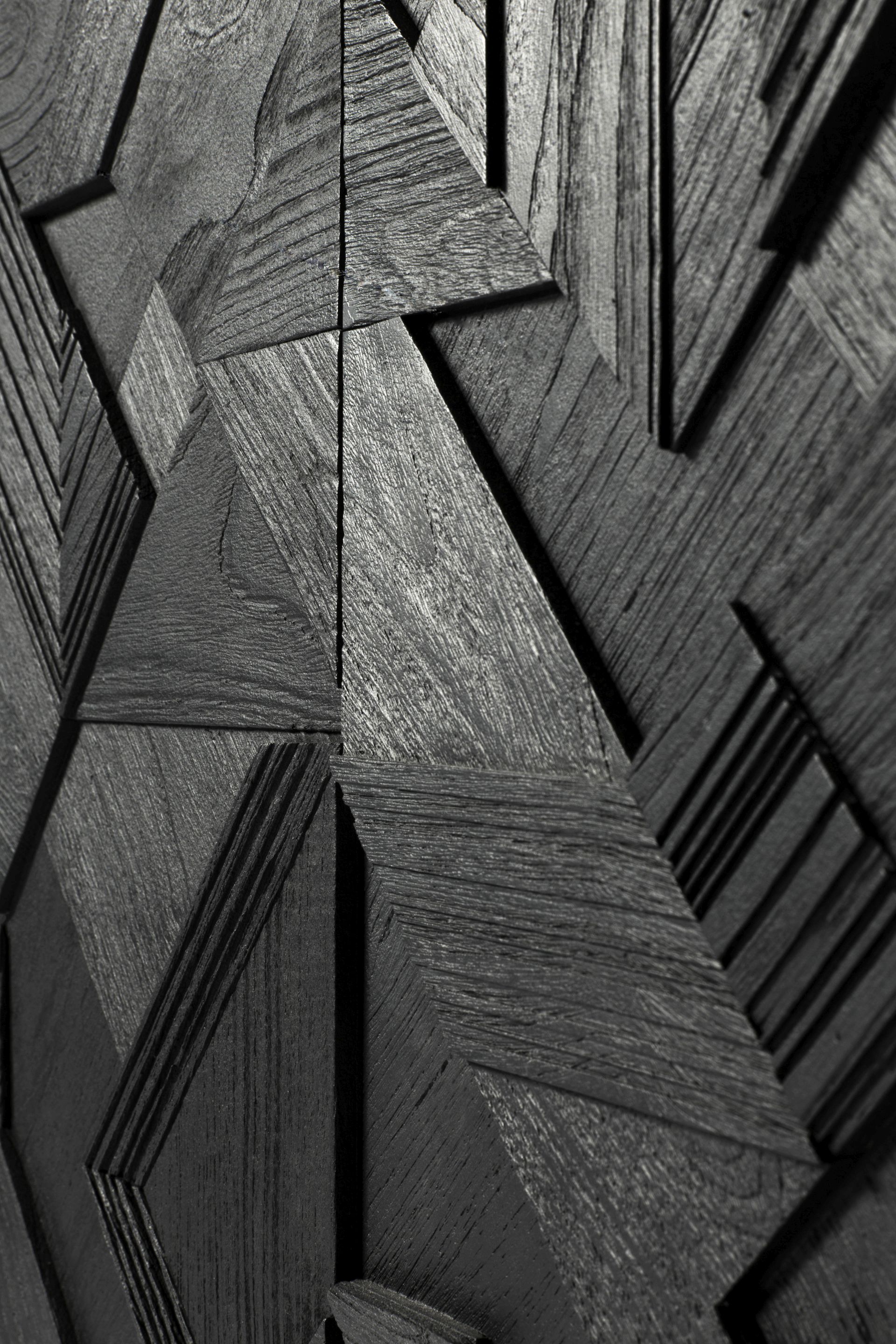 Detailaufnahme der grafischen Teakholzfront der schwarzen Ethnicraft Anrichte mit geometrischen Mustern und Holzmaserung.