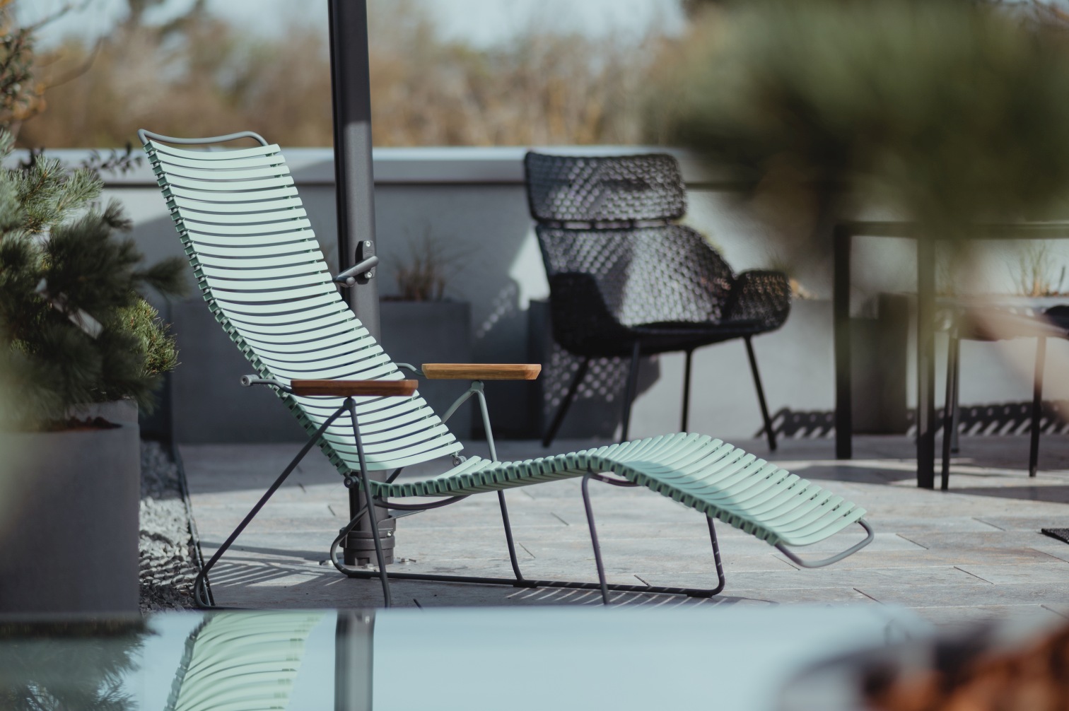 Click Sunrocker Sonnenliege von Houe, dunkelgraues Gestell, hellgrüne Sitzfläche, für Garten und Terrasse.