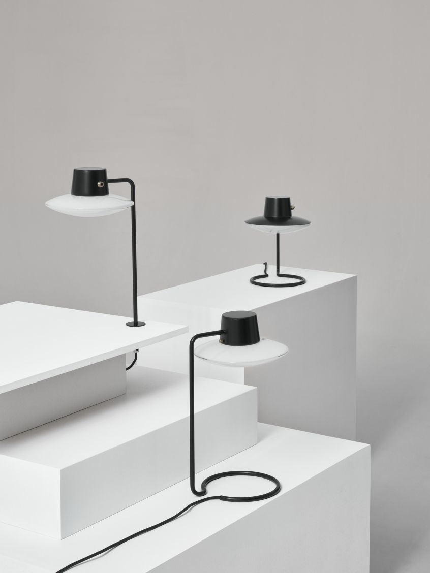 AJ Oxford Tischleuchte von Louis Poulsen: Schwarze Metall-Tischlampe mit Opalglas-Schirm auf weißen Podesten. Designleuchte für modernes Ambiente.