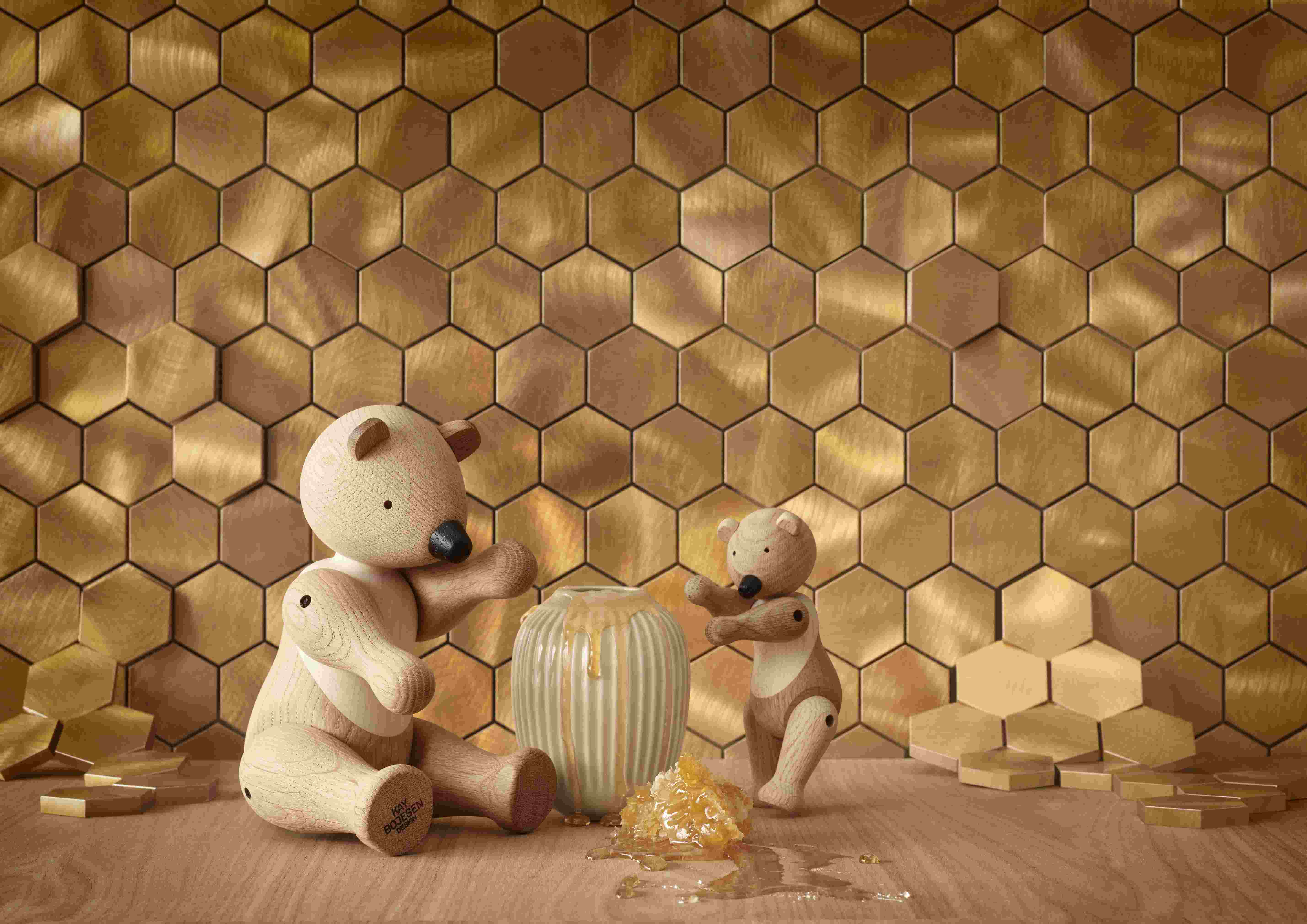 Holzspielzeug Bären von Kay Bojesen mit Honigwabe und Honigtopf vor goldenem Hintergrund.