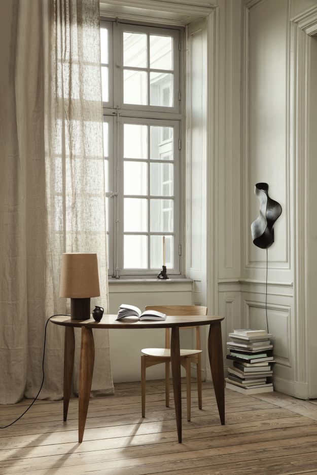 Schwarze Oyster Wandleuchte von Ferm Living an einer weißen Wand in einem hellen Raum.