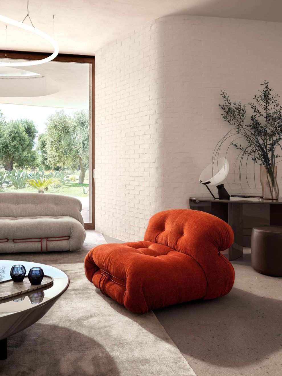 Oranger Cassina Soriana Sessel im Wohnzimmer mit passendem Sofa und Couchtisch, modernes Möbeldesign.