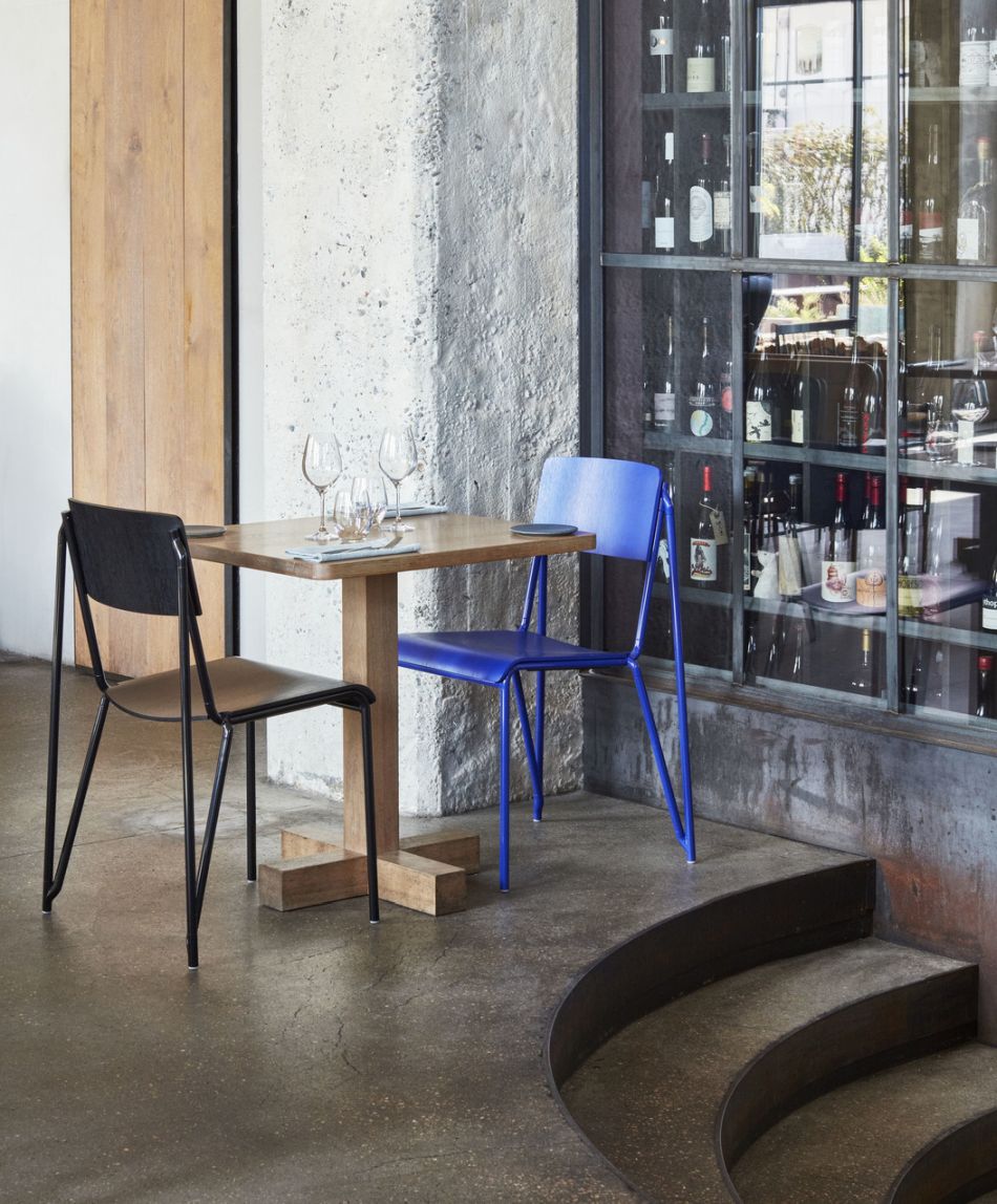 Zwei Hay Stühle, ein Petit Standard Stuhl in Blau und Schwarz, an einem Holztisch.