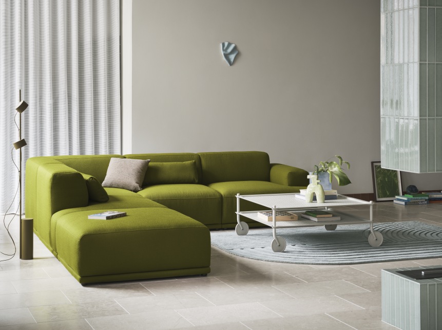 Wohnzimmer mit grünem Sofa und Muuto Flow Coffee Table Couchtisch auf Rollen.