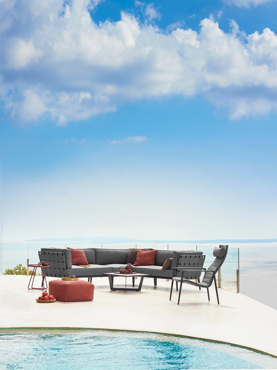 Conic Outdoor 2-Sitzer Modulsofa links von Cane-Line mit grauen Polstern und roten Kissen auf Terrasse.