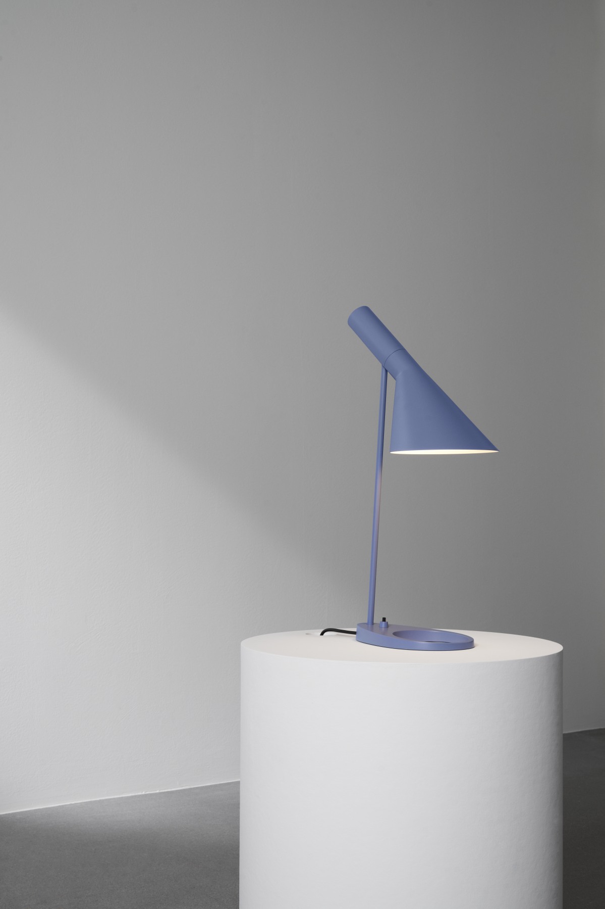 AJ Tischleuchte in Blau auf weißem Sockel. Designklassiker für Schreibtisch und Nachttisch.
