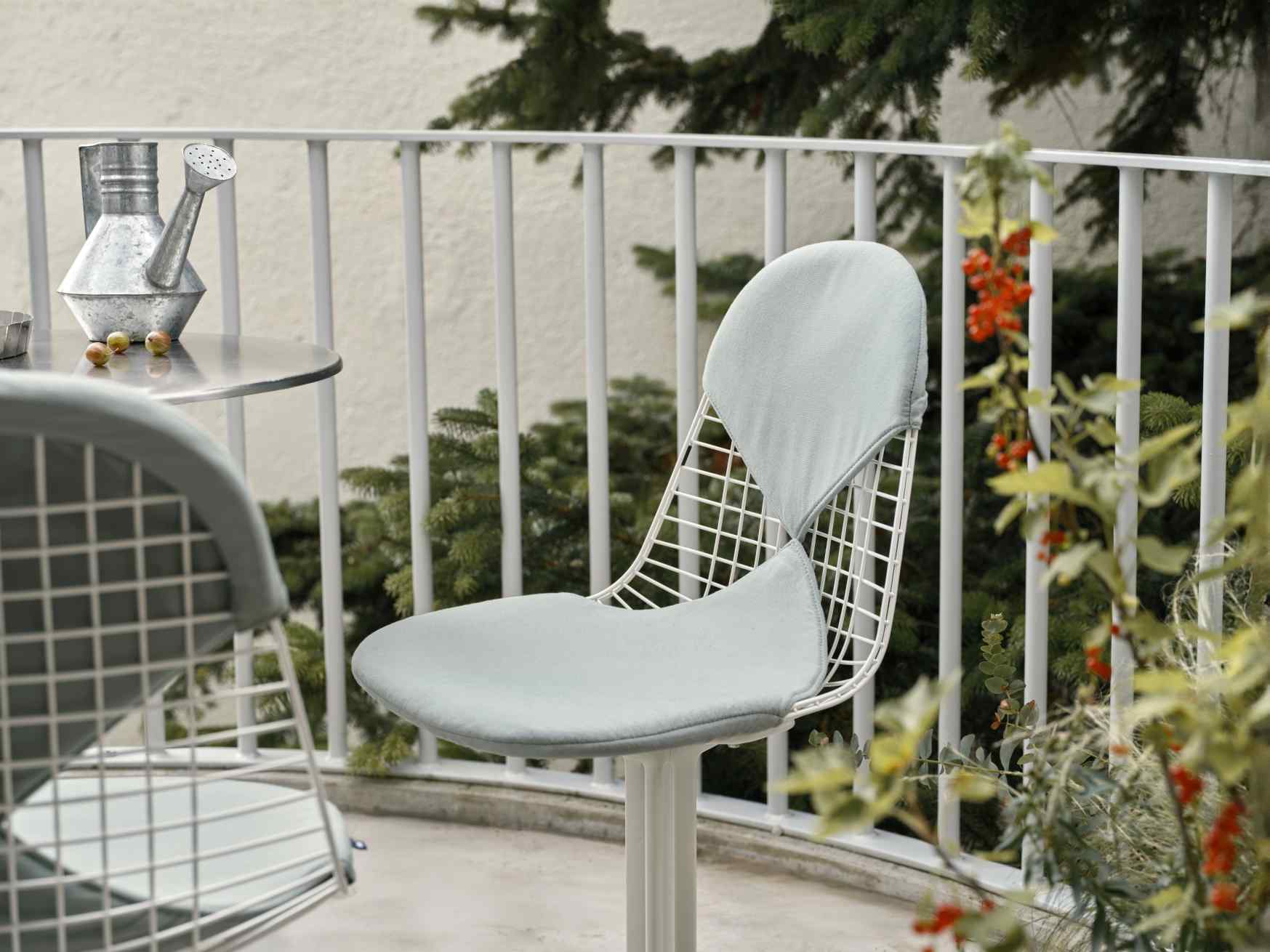Vitra Wire Chair Bikini Outdoor, weißer Drahtstuhl mit hellblauem Sitzkissen und Rückenpolster auf Balkon.