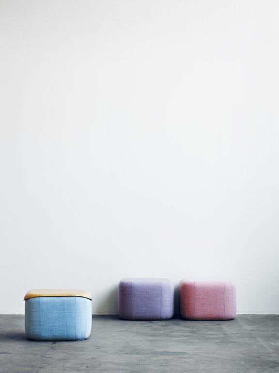 Drei gepolsterte Hocker, darunter ein blauer Quadro Hocker mit Holzplatte, lila und rosa Sitzhocker.