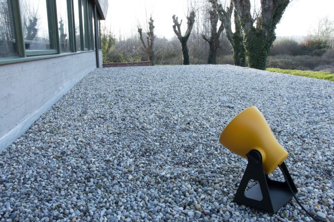 Gelbe Mini Frog Outdoor Leuchte von Martinelli Luce auf Kiesboden vor einem Haus.