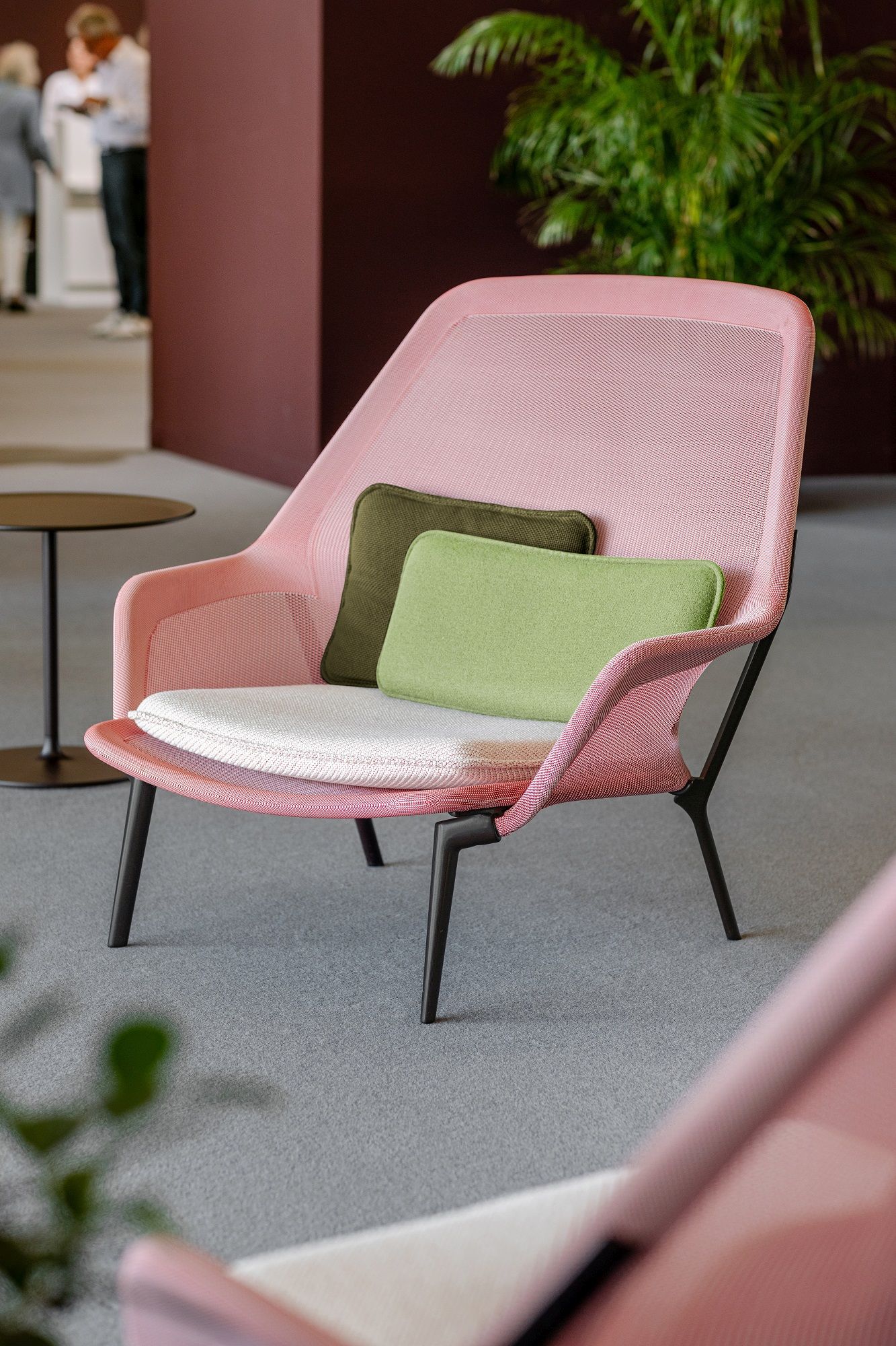 Nahaufnahme des Vitra Slow Chair Sessels in Rosa mit grünen Kissen, ideal für modernes Wohnen.