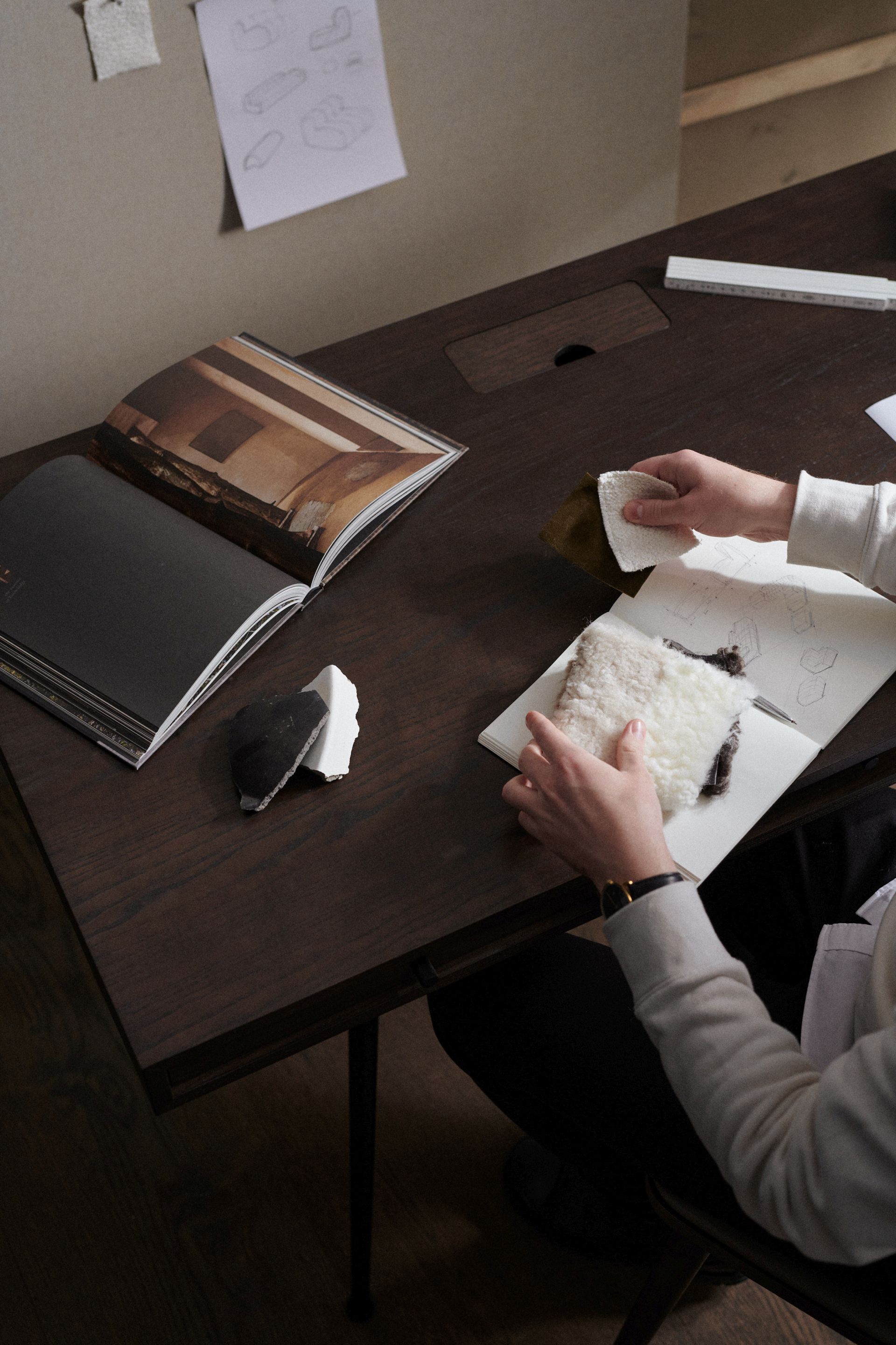 JFK Büroschreibtisch Norr11 mit Standard Beinen aus dunklem Holz, umgeben von Designelementen und Stoffmustern.