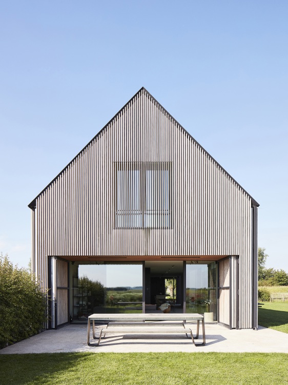 Extremis Hopper Picknickbank aus Holz und Metall im Außenbereich vor modernem Haus mit Glasfront.