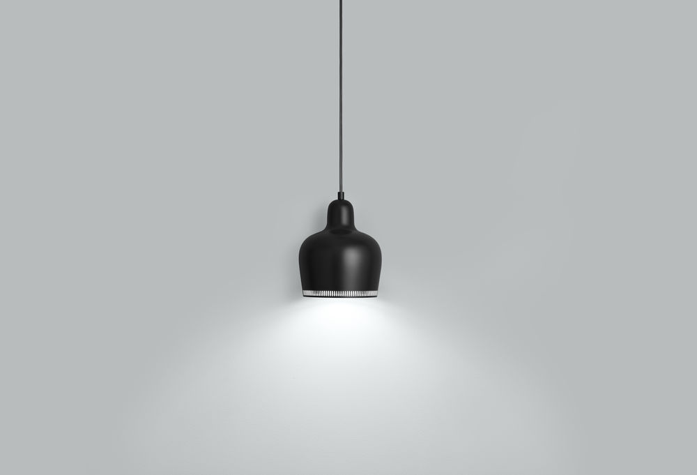 Schwarze A330S Pendelleuchte von Artek mit warmem Lichtkegel vor grauem Hintergrund. Design Lampe.
