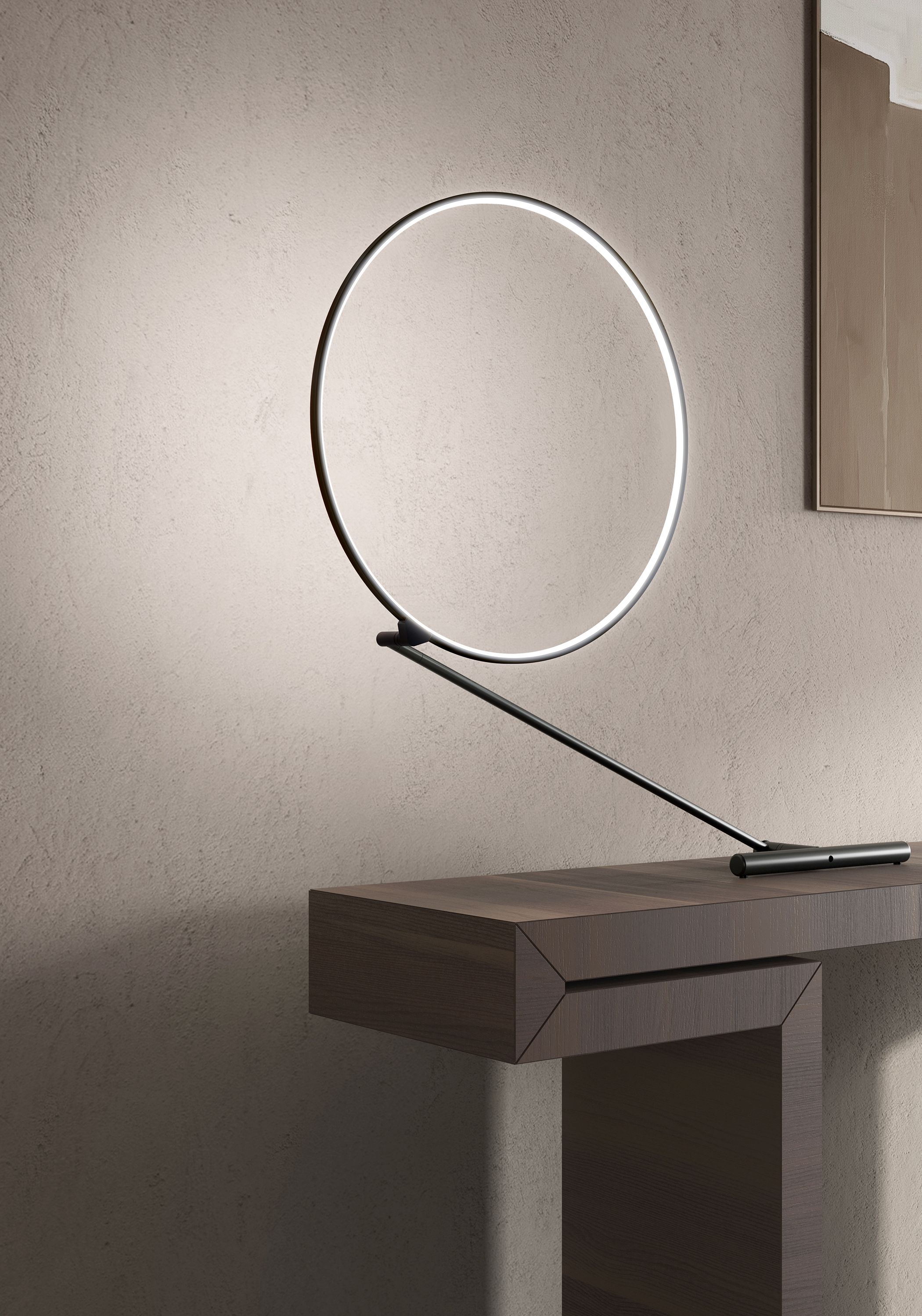 Poise Tischleuchte von Kdln: Moderne LED-Tischlampe mit kreisförmigem Leuchtkörper auf einem dunklen Holztisch.
