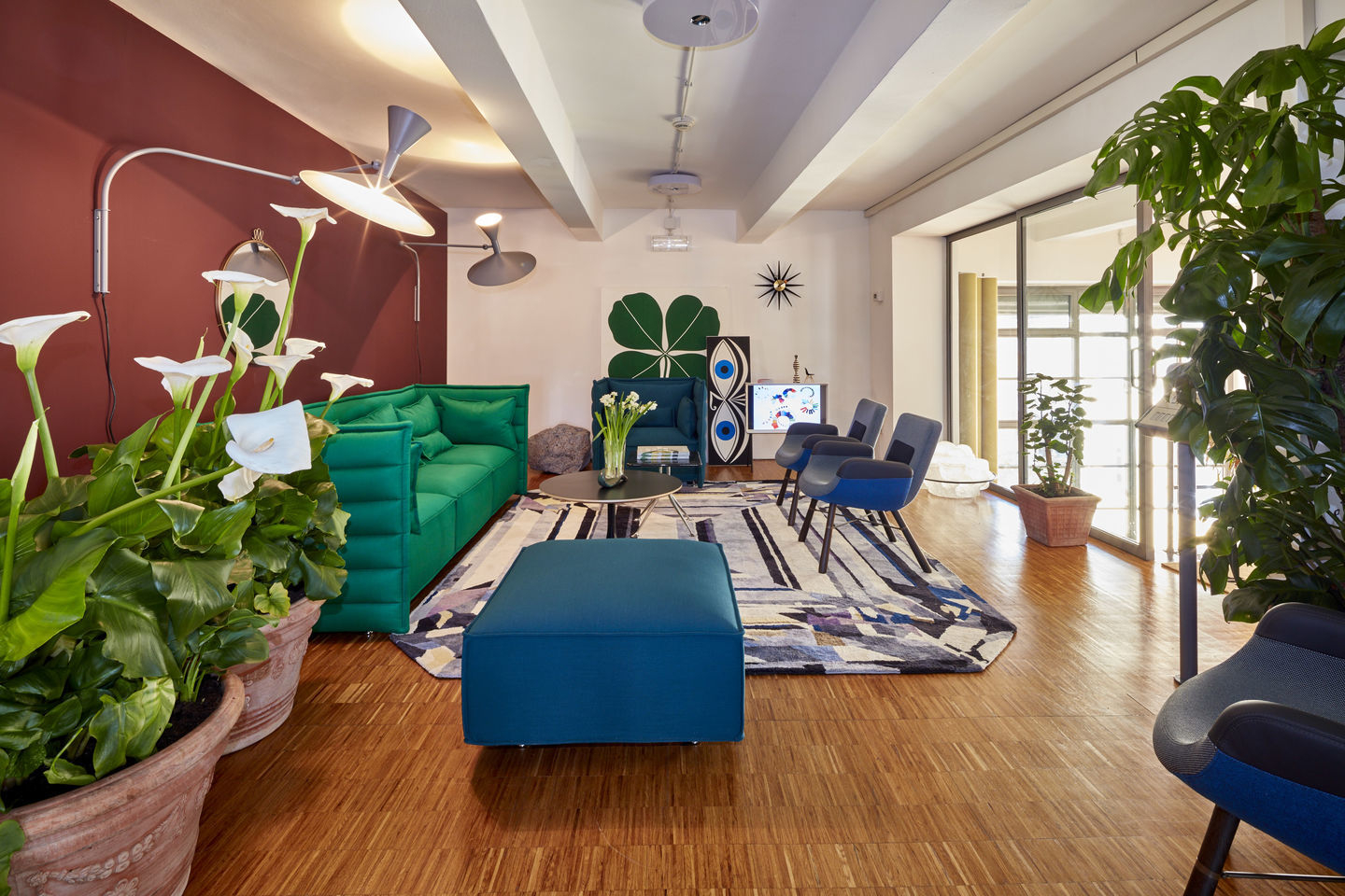 Wohnzimmer mit East River Chair Sessel von Vitra in blau, grünes Sofa und modernen Möbeln.