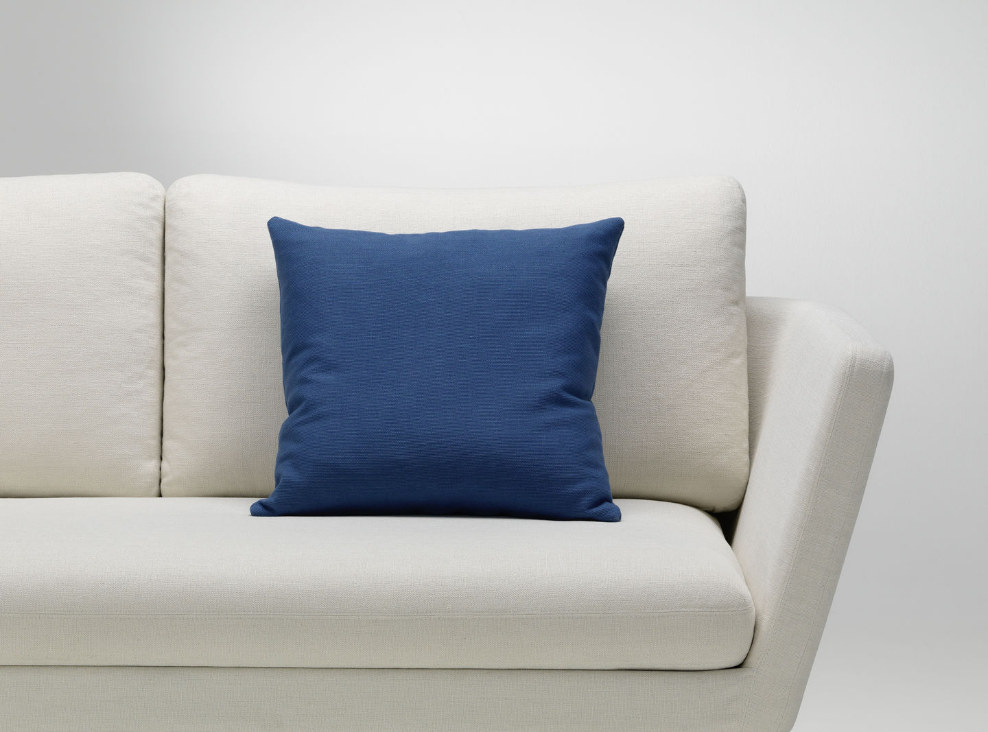Blaues Vitra Kissen auf einem hellen Sofa, modernes Wohnaccessoire für stilvolles Wohnzimmer Design.