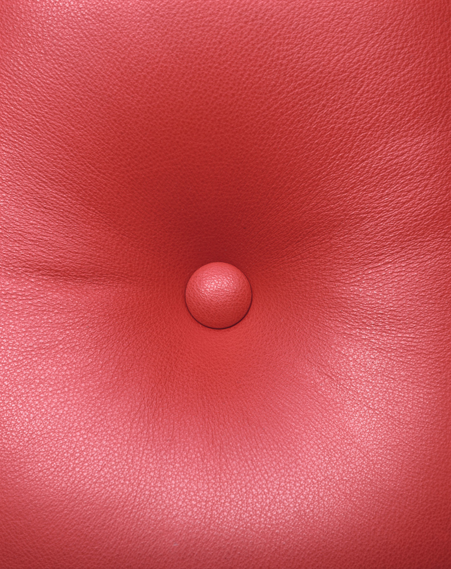 Detailaufnahme: Rotes Lederpolster mit Knopf des Vitra Lobby Chair ES104 Stuhls.