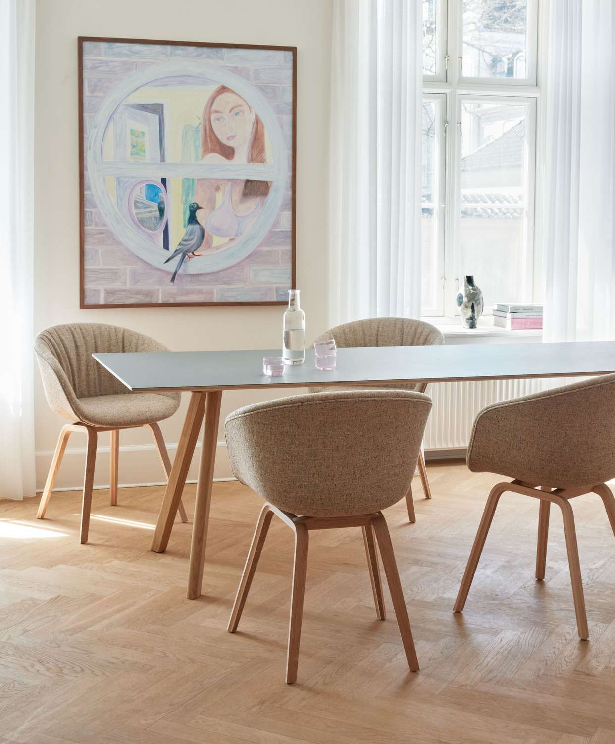 Esszimmer mit vier "About a Chair AAC23" Stühlen mit Stoffbezug und Holzbeinen.
