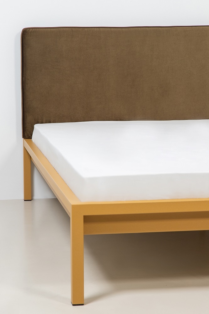 Pure Bett von Hans Hansen, Stahl pulverbeschichtet in Sand Gold mit braunem Polsterkopfteil und weißer Matratze.
