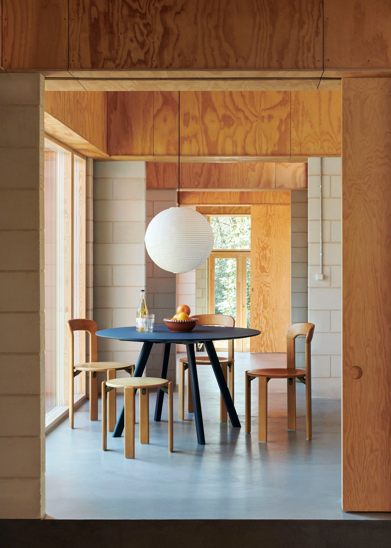 Esszimmer mit blauem Esstisch, Holzstühlen und einem hellen Rey Stool Hocker von Hay.